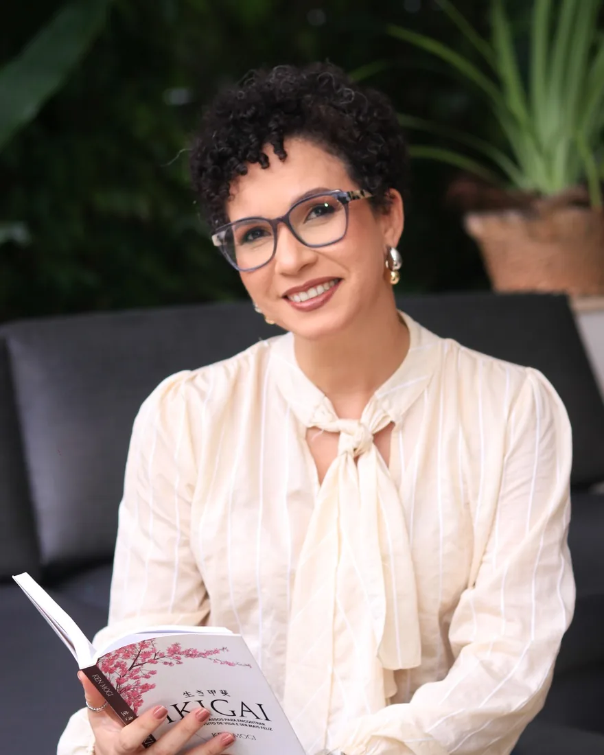 Nai Moraes segurando um livro, sorrindo